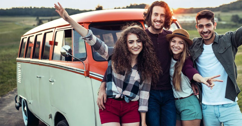 Junge Meschen machen Selfie als Gruppe vor stylischem Kleinbus.